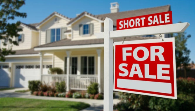 A short sale sign in front of a house for sale