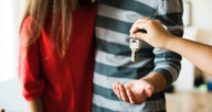 A seller handing keys to new buyers after deciding to sell rather than refinance a mortgage.