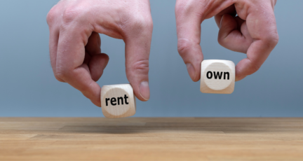 Hands holding dice that say rent and own, as you weigh the option of rent to own homes.